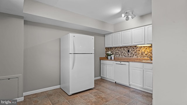 kitchen featuring baseboards, decorative backsplash, white appliances, white cabinetry, and a sink