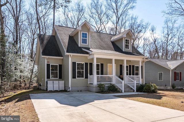 new england style home featuring covered porch and roof with shingles