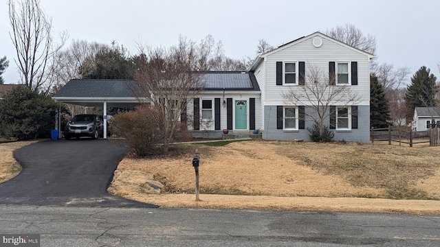 split level home featuring a carport, fence, brick siding, and driveway