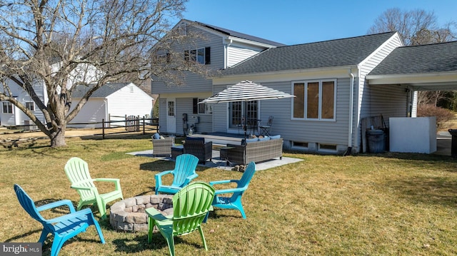 back of property featuring an outdoor living space with a fire pit, fence, roof with shingles, a yard, and a patio area