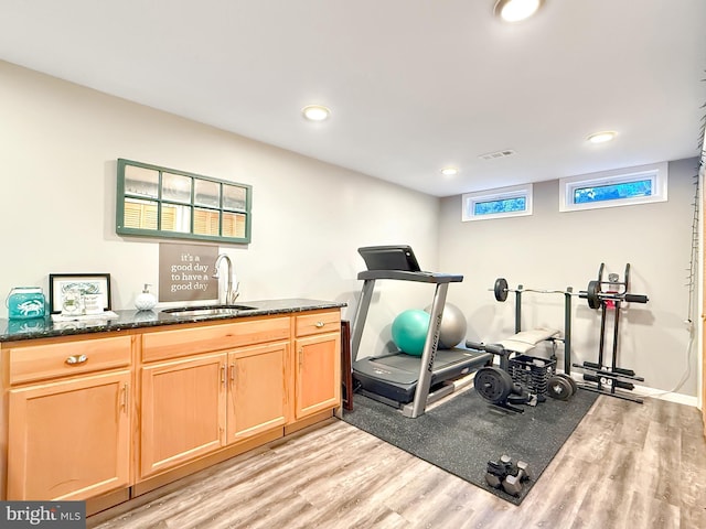 workout room with recessed lighting, visible vents, light wood finished floors, and a sink