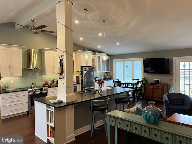 kitchen featuring dark countertops, stainless steel appliances, white cabinetry, wall chimney exhaust hood, and a sink