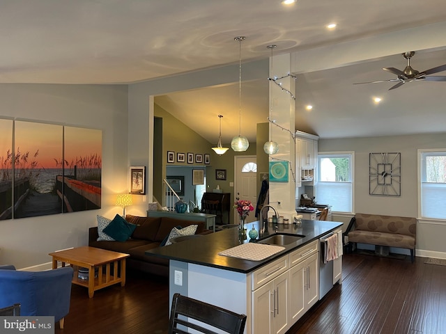 kitchen with a sink, vaulted ceiling, dark wood-type flooring, dark countertops, and open floor plan