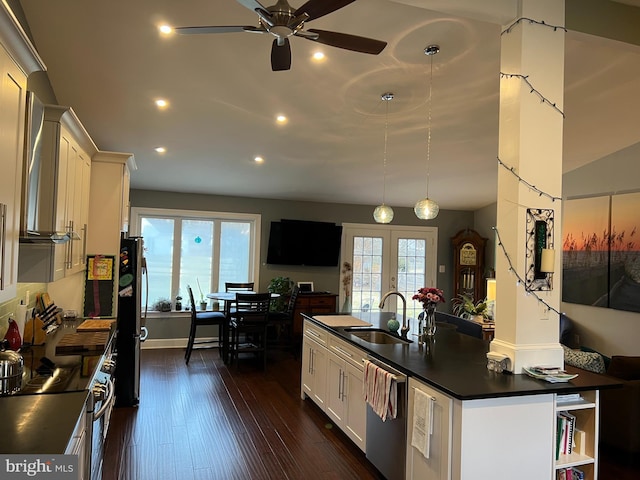 kitchen with a sink, stainless steel appliances, dark countertops, and white cabinetry