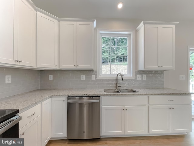 kitchen featuring light stone countertops, stainless steel appliances, a sink, white cabinetry, and decorative backsplash