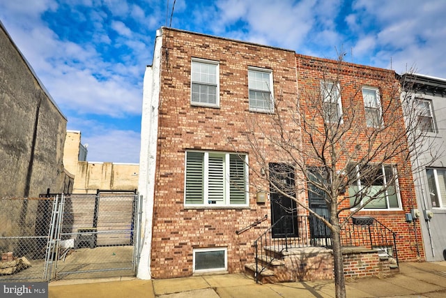 view of property featuring a gate, fence, and brick siding