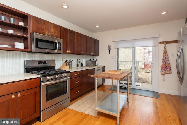 kitchen featuring stainless steel appliances, backsplash, a sink, and light countertops