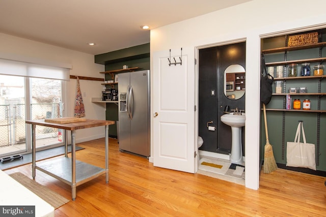 kitchen featuring light wood-style flooring, recessed lighting, a sink, stainless steel fridge with ice dispenser, and open shelves