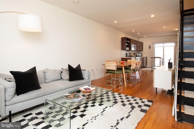 living room with light wood-style flooring, stairs, baseboards, and recessed lighting