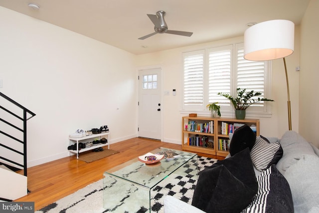 living room with stairs, ceiling fan, wood finished floors, and baseboards