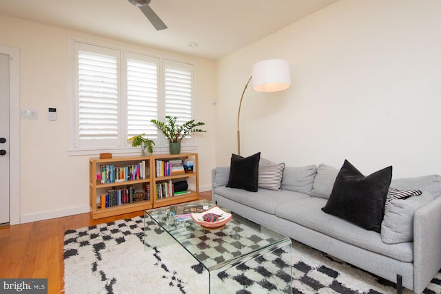 living room featuring a ceiling fan, baseboards, and wood finished floors