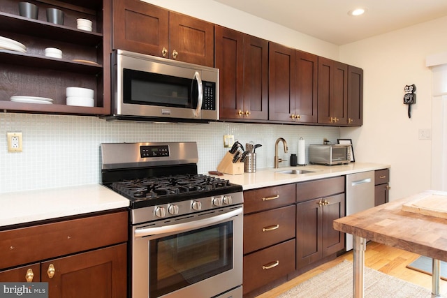 kitchen with light countertops, appliances with stainless steel finishes, a sink, and decorative backsplash