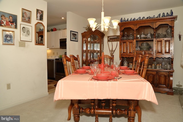 dining area featuring a chandelier, light colored carpet, and baseboards