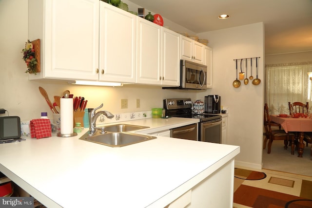 kitchen featuring recessed lighting, stainless steel appliances, a sink, white cabinets, and light countertops