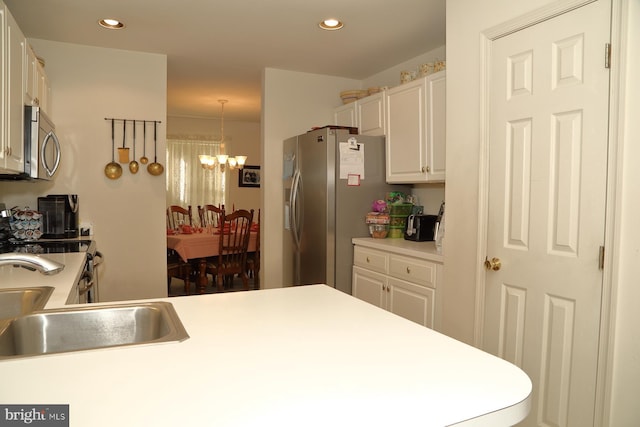 kitchen featuring light countertops, appliances with stainless steel finishes, a sink, and white cabinetry