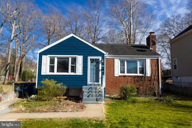 bungalow-style house featuring a chimney, a front lawn, and brick siding