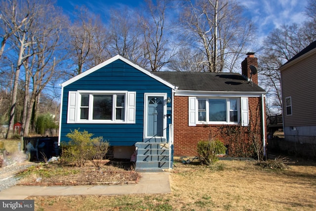 bungalow-style house featuring brick siding and a chimney