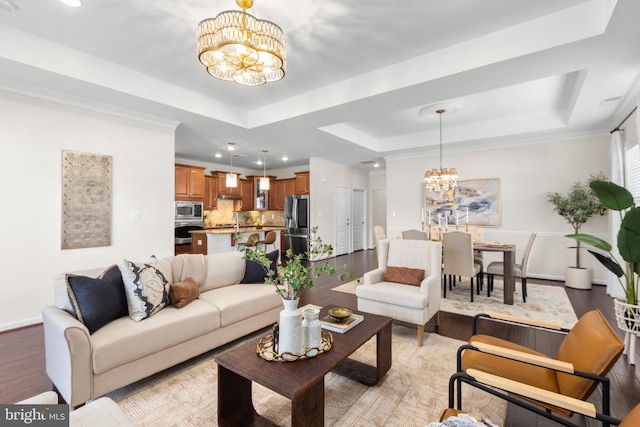 living area featuring recessed lighting, a notable chandelier, baseboards, light wood-type flooring, and a raised ceiling