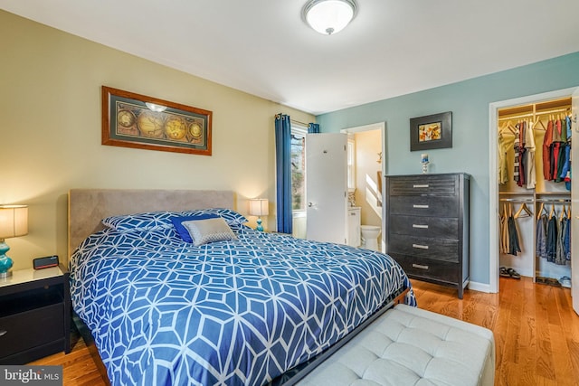 bedroom featuring ensuite bath, a spacious closet, wood finished floors, and a closet