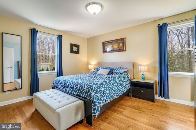 bedroom with multiple windows, wood finished floors, and baseboards