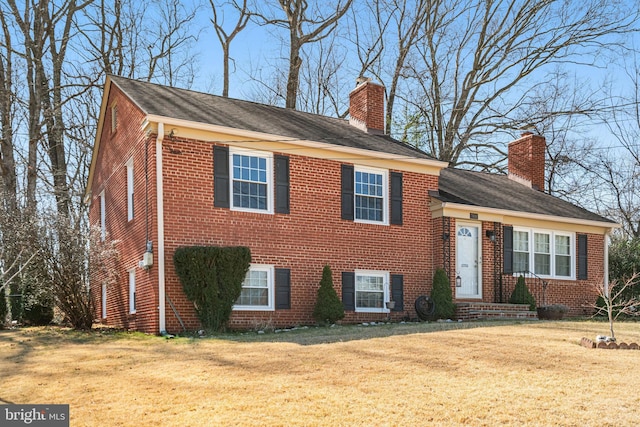 view of front of house with a front lawn, brick siding, and a chimney