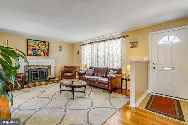 living area with a glass covered fireplace, baseboards, and wood finished floors