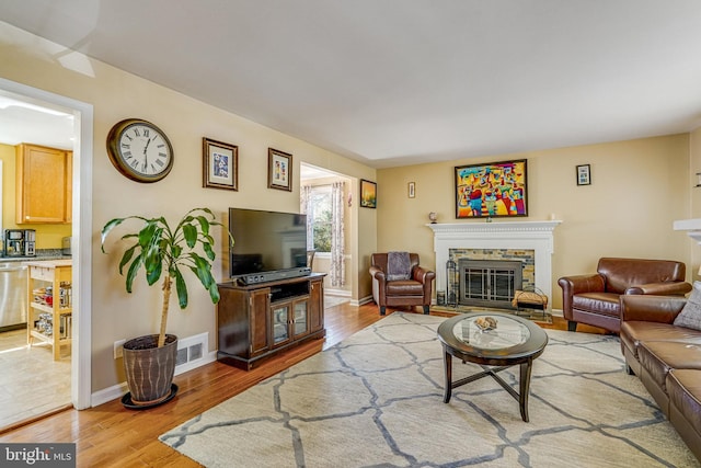 living room with wood finished floors, a fireplace, visible vents, and baseboards