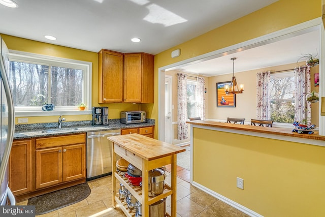 kitchen with dishwasher, brown cabinets, a wealth of natural light, and a sink