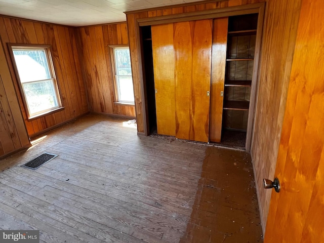 unfurnished bedroom featuring hardwood / wood-style floors, multiple windows, a closet, and visible vents