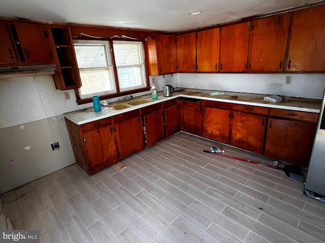 kitchen with light countertops, light wood-type flooring, a sink, and brown cabinets