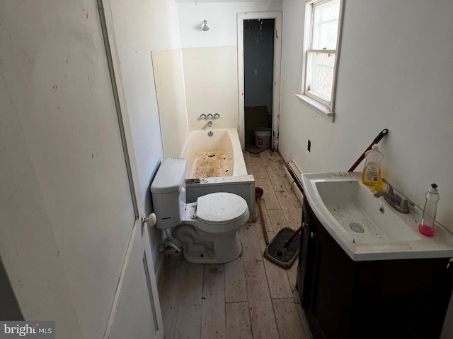 bathroom with toilet, vanity, hardwood / wood-style floors, and a bathing tub