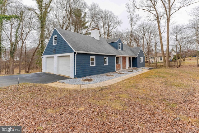 view of front facade featuring a shingled roof, a detached garage, a chimney, and brick siding