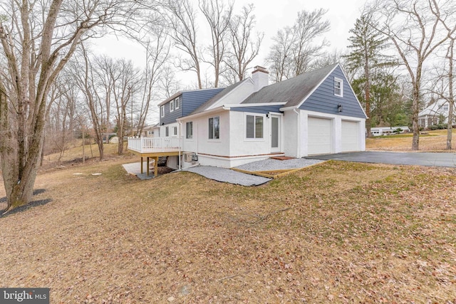 1225 Dogwood Dr, West Chester, PA 19380 - view of property exterior featuring driveway, a chimney, a lawn, and stucco siding