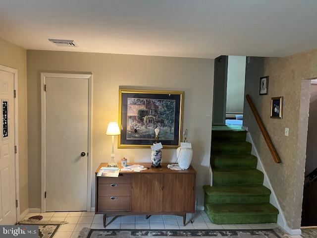 stairs with baseboards, visible vents, and tile patterned floors