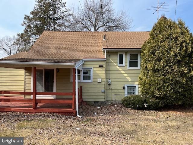 rear view of property with a shingled roof and crawl space