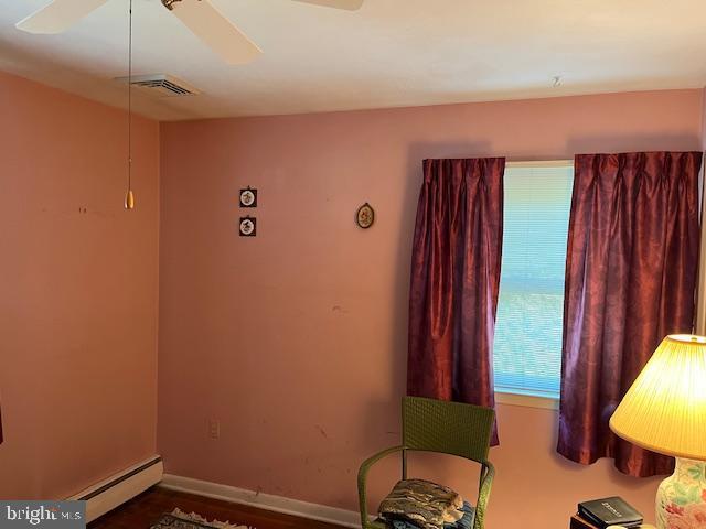 living area with a baseboard radiator, visible vents, ceiling fan, and baseboards