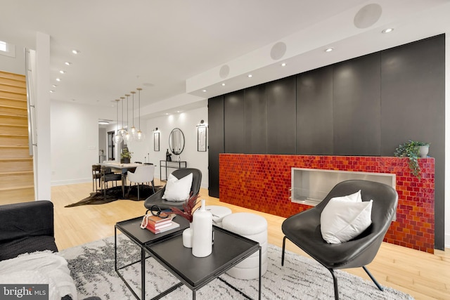 living area featuring light wood finished floors, stairs, baseboards, and recessed lighting