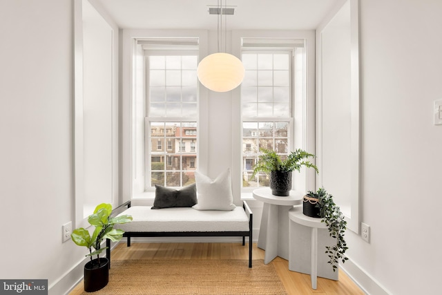 sitting room with wood finished floors, visible vents, and baseboards