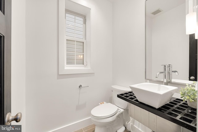 half bathroom with visible vents, a sink, and toilet