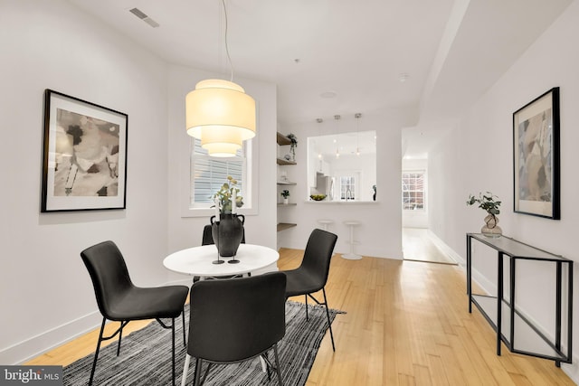 dining room with light wood finished floors, baseboards, and visible vents