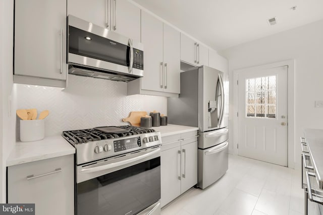 kitchen with light stone countertops, visible vents, appliances with stainless steel finishes, and decorative backsplash