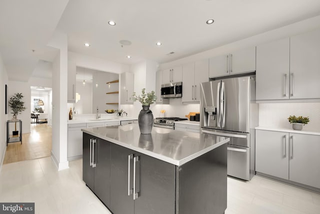 kitchen with recessed lighting, light countertops, appliances with stainless steel finishes, a kitchen island, and a sink