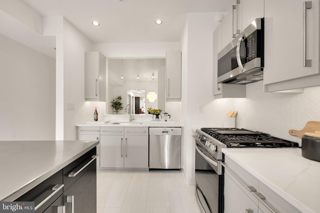 kitchen featuring tasteful backsplash, stainless steel appliances, light countertops, a sink, and recessed lighting