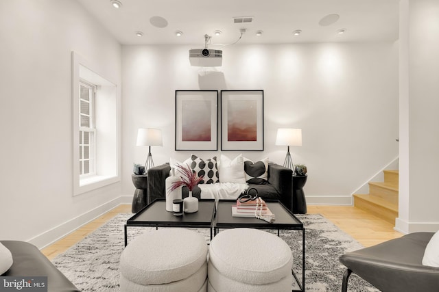 living room with light wood-style flooring, stairway, visible vents, and baseboards