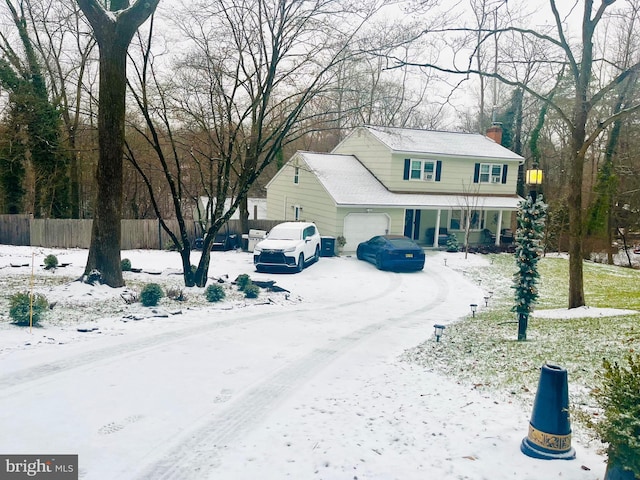 view of front of house with a garage, covered porch, a chimney, and fence