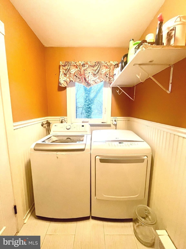 clothes washing area with laundry area, wainscoting, and washing machine and dryer