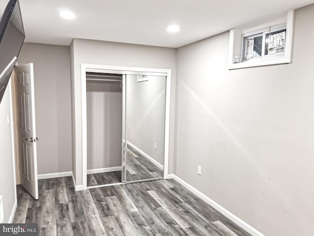 unfurnished bedroom featuring a closet, baseboards, wood finished floors, and recessed lighting