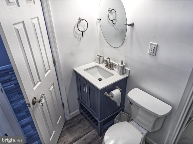 half bathroom featuring wood finished floors, vanity, and toilet