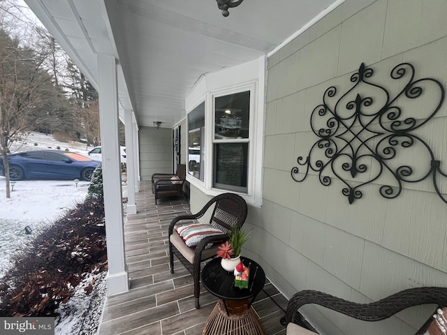 snow covered deck featuring covered porch