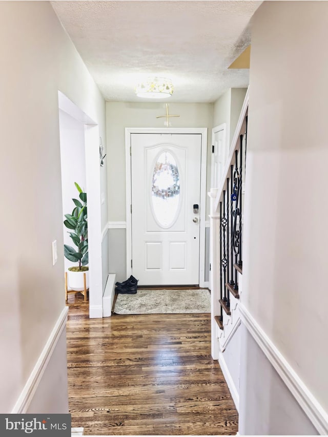 entrance foyer featuring baseboards, stairway, a textured ceiling, and wood finished floors